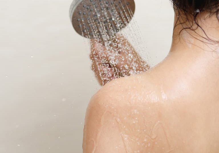 woman taking shower and washing hair with shampoo